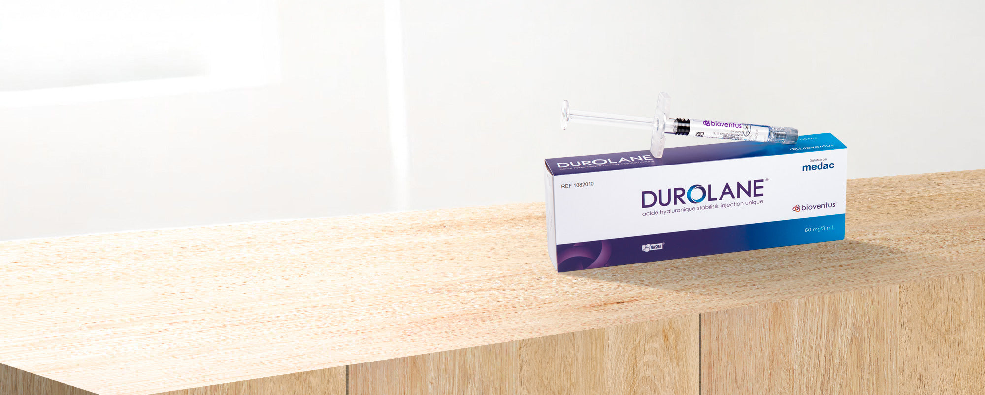Boîte Durolane avec seringue d’acide hyaluronique posée sur un meuble, illustrant le packaging du dispositif injectable.