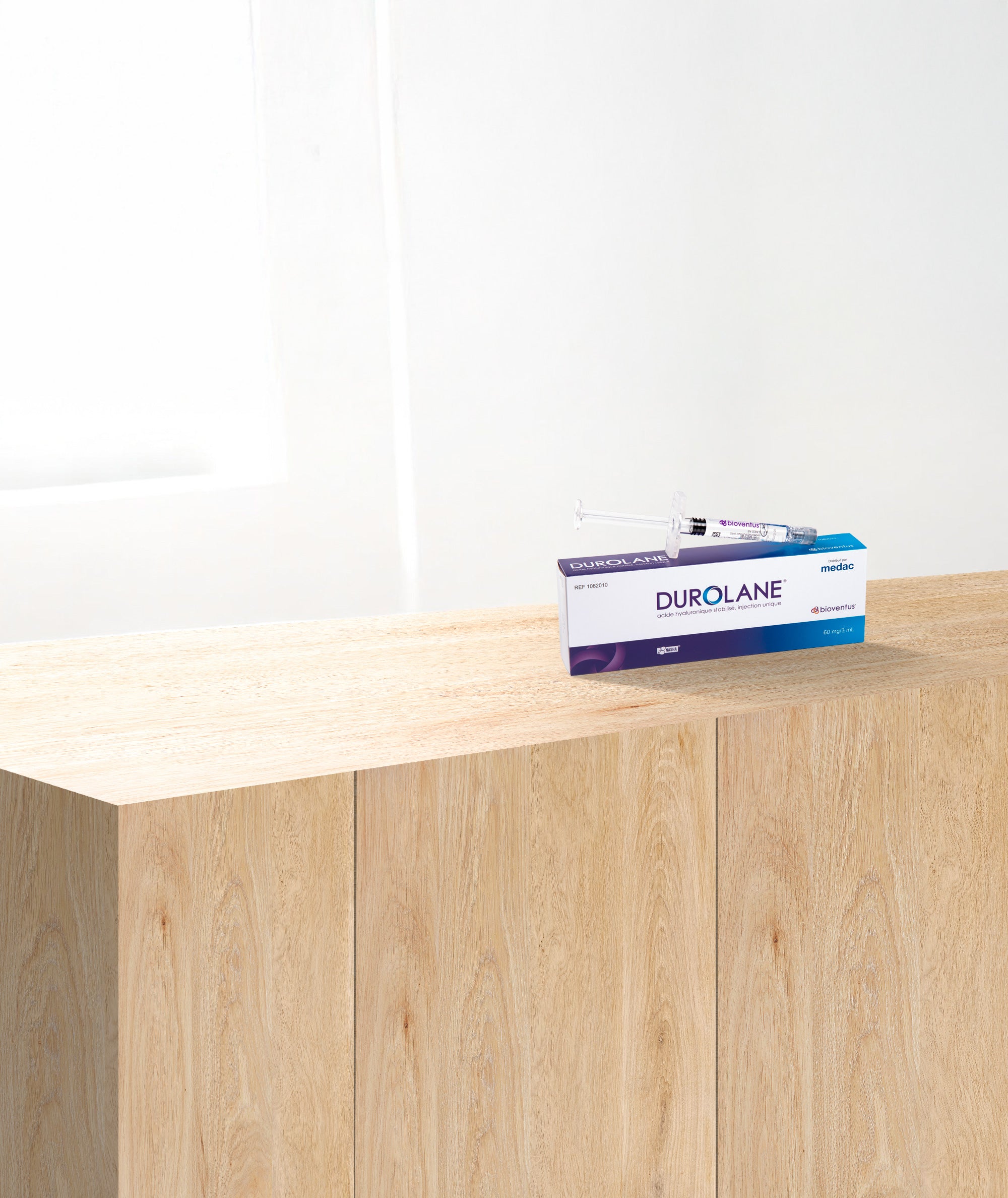 Boîte Durolane avec seringue d’acide hyaluronique posée sur un meuble, illustrant le packaging du dispositif injectable.