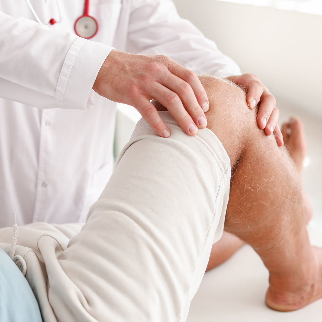 Médecin en blouse blanche examinant le genou d’un patient allongé, dans un contexte de douleur articulaire ou d’injection intra-articulaire.